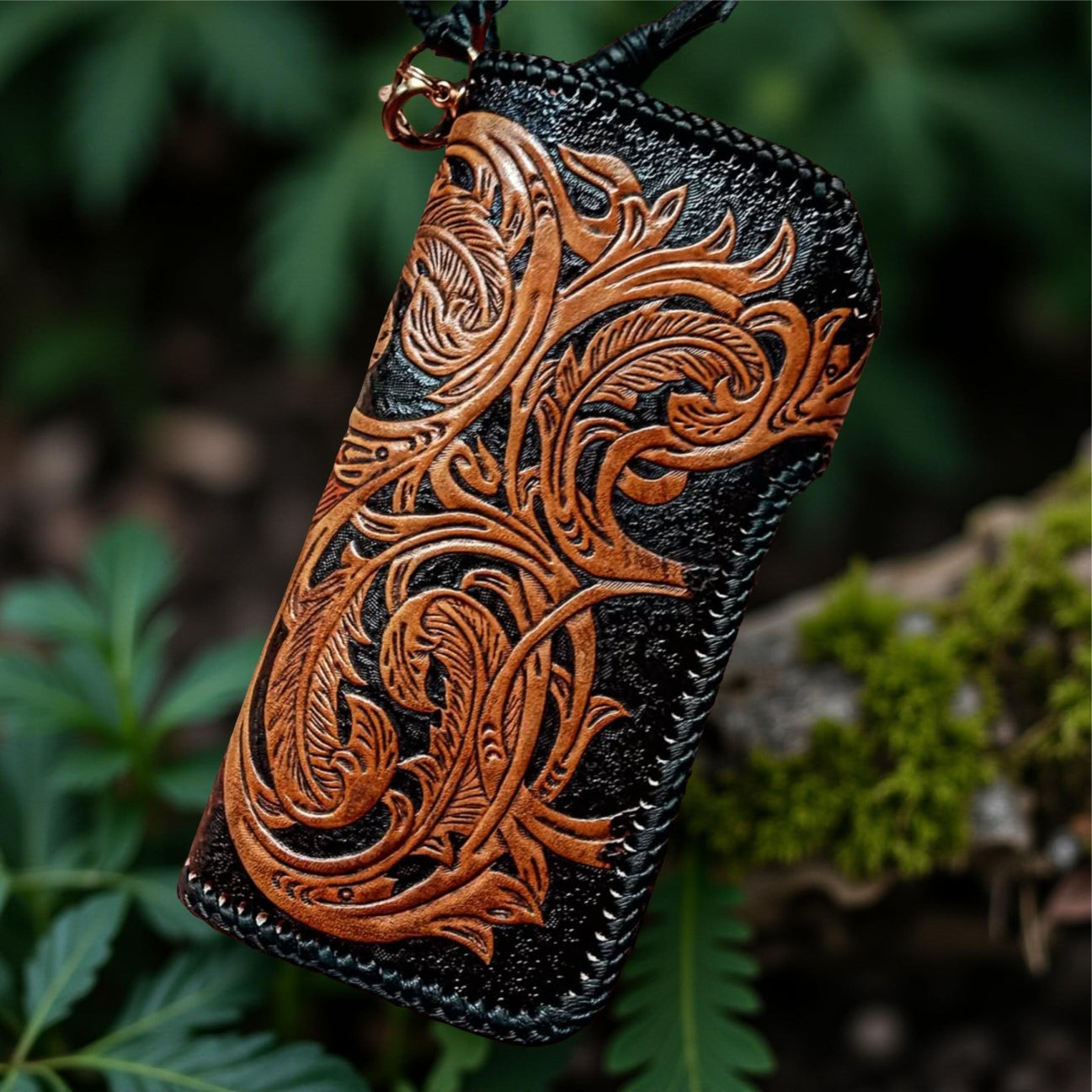 Leather wallet with intricate brown embossed design on a green natural background