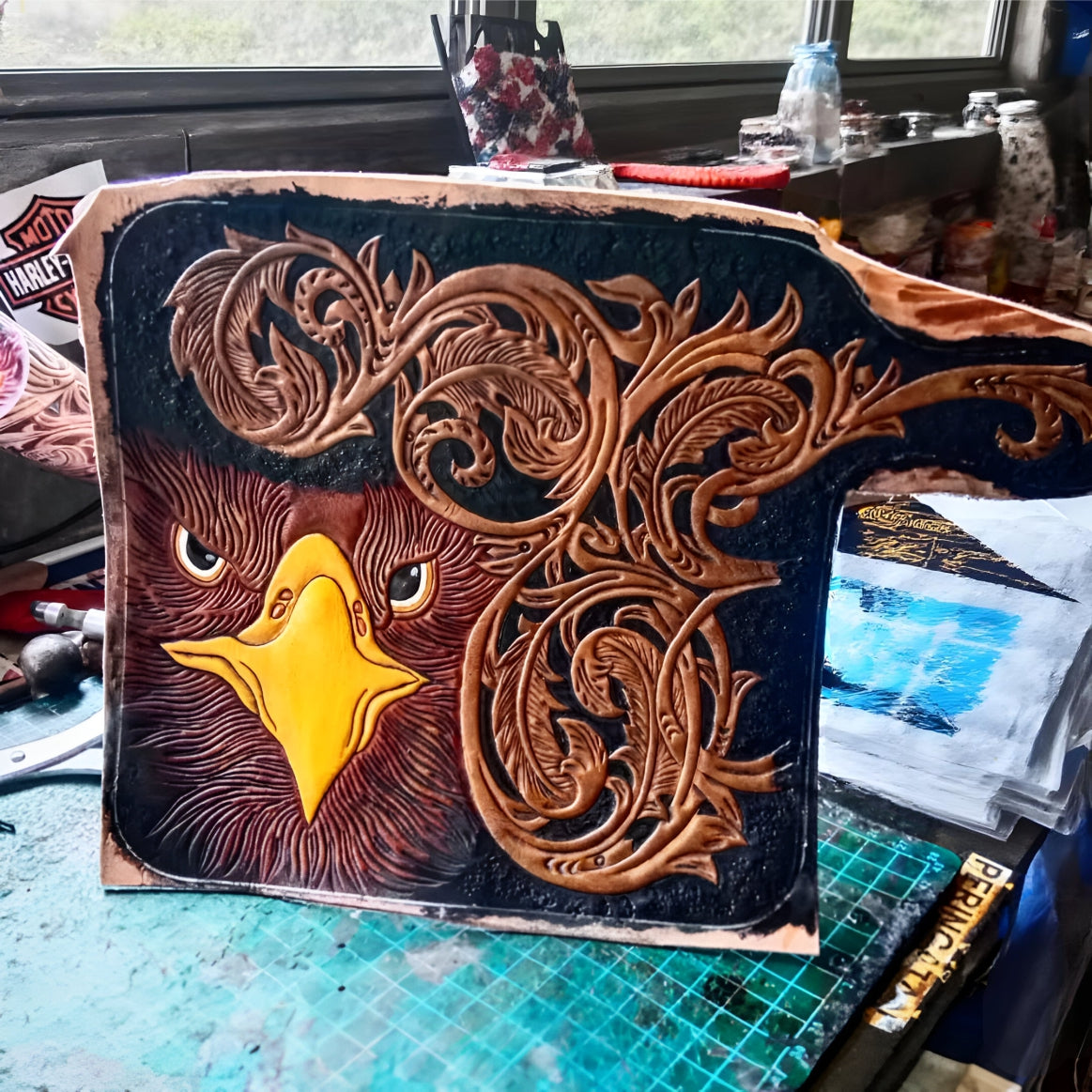 Decorative leather piece with an eagle design on a workbench.