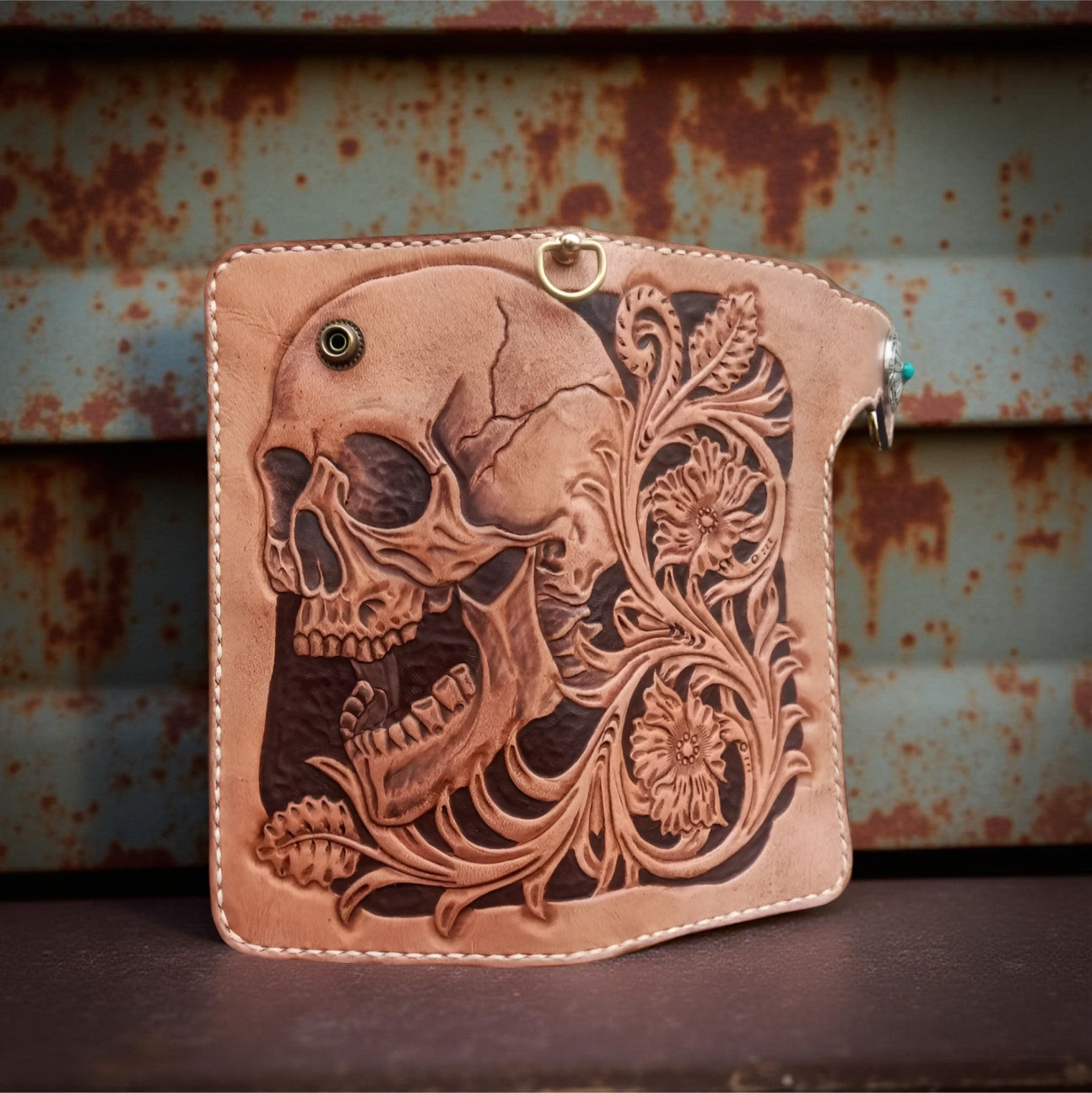 Middle brown leather wallet with skull design and turquoise stone on a textured surface