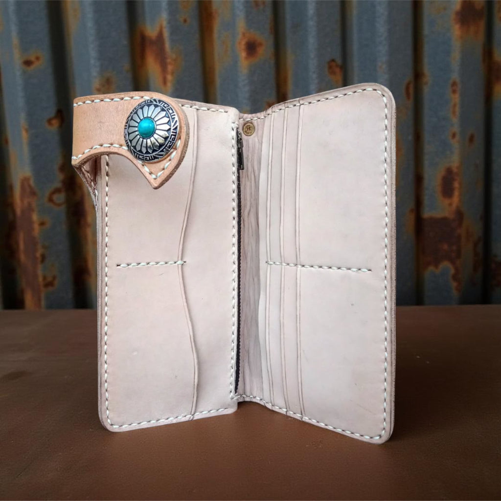 Inside brown leather wallet with skull design and turquoise stone on a textured surface
